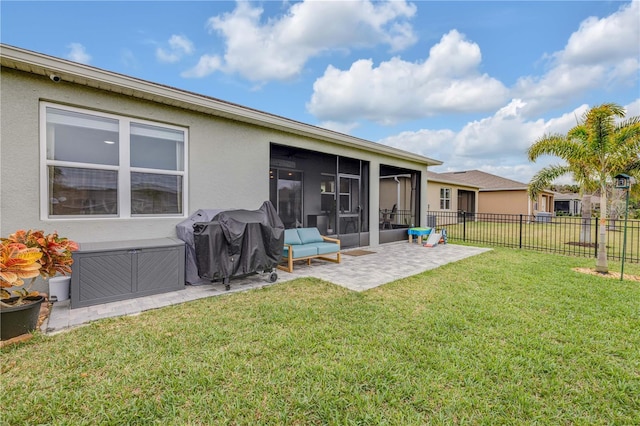 rear view of property with a sunroom, a patio area, a lawn, and stucco siding