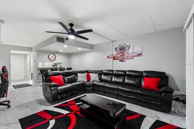 living room with a textured ceiling, marble finish floor, visible vents, and a ceiling fan