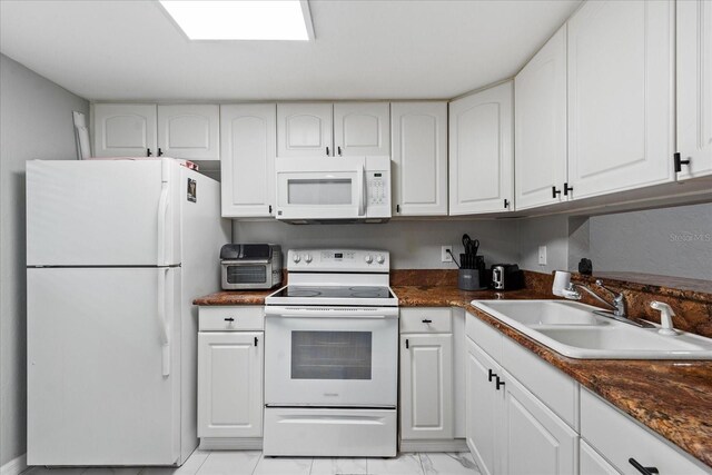 kitchen with white appliances, a sink, and white cabinetry