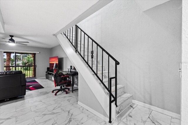 staircase featuring marble finish floor, a textured wall, and baseboards