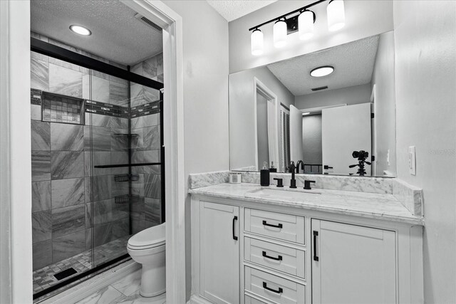 bathroom with a textured ceiling, toilet, vanity, visible vents, and a shower stall