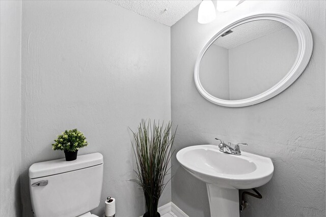 half bath featuring a textured ceiling and toilet