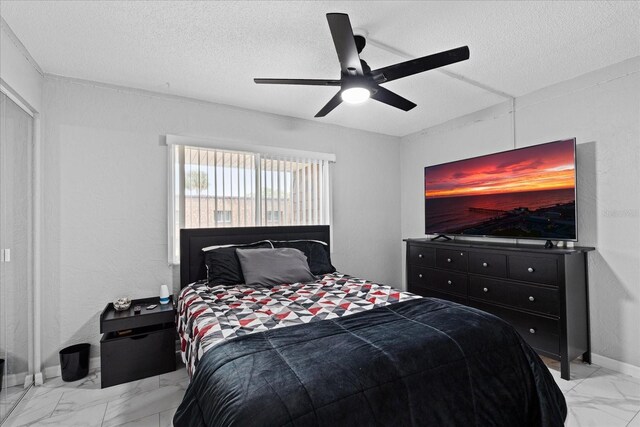 bedroom with a textured ceiling, marble finish floor, a ceiling fan, and baseboards