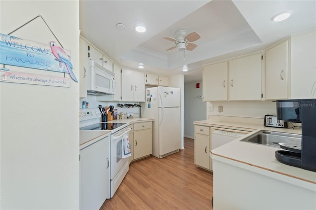 kitchen with light wood-type flooring, light countertops, white appliances, and a raised ceiling