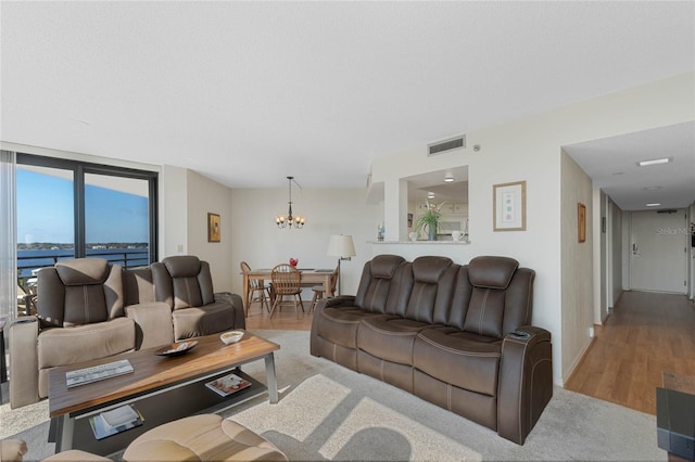 living area featuring visible vents, a water view, a textured ceiling, wood finished floors, and a chandelier