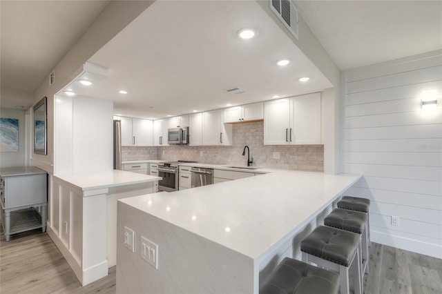 kitchen featuring a peninsula, white cabinetry, appliances with stainless steel finishes, and light countertops