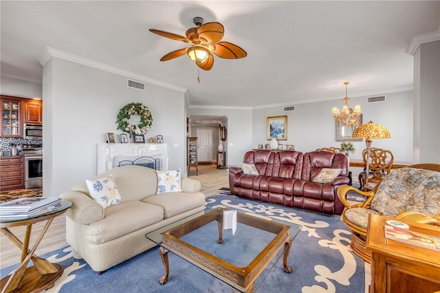 living room featuring ceiling fan with notable chandelier, a fireplace, visible vents, and crown molding