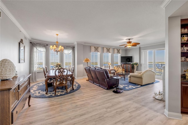 living area with baseboards, light wood-style flooring, a textured ceiling, crown molding, and ceiling fan with notable chandelier