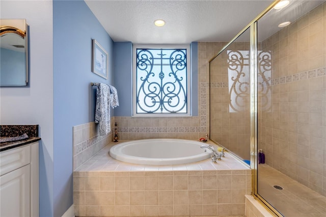 full bathroom featuring a textured ceiling, a shower stall, vanity, and a bath