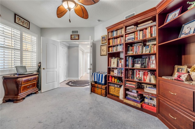 sitting room featuring light carpet, a ceiling fan, visible vents, and a textured ceiling