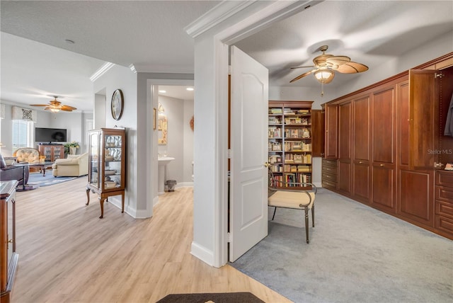 hallway featuring light wood-type flooring, crown molding, a textured ceiling, and baseboards