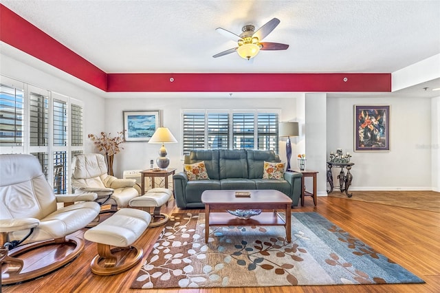 living room featuring plenty of natural light, a textured ceiling, baseboards, and wood finished floors