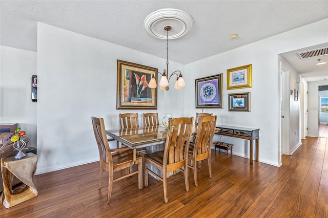 dining space with baseboards, a textured ceiling, an inviting chandelier, and wood finished floors