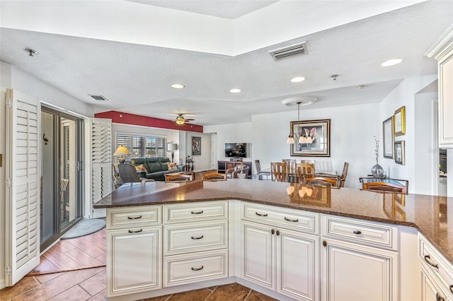 kitchen featuring a ceiling fan, visible vents, open floor plan, and cream cabinetry