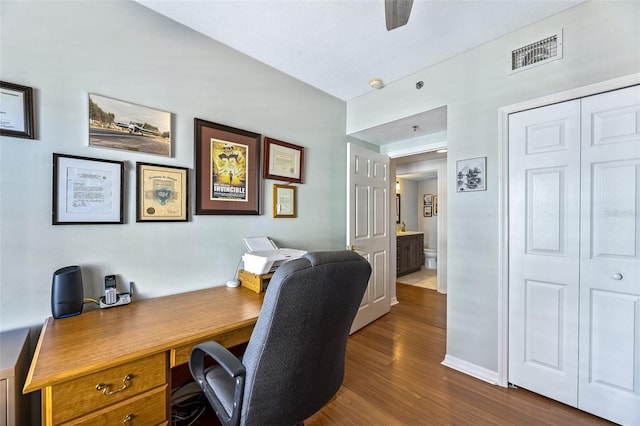 home office featuring a ceiling fan, visible vents, dark wood finished floors, and baseboards