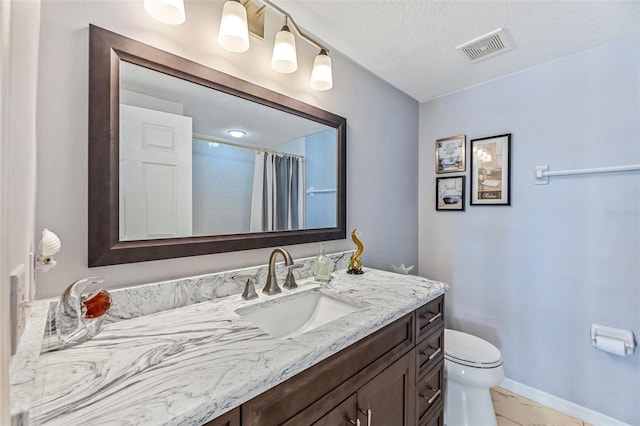 bathroom with visible vents, toilet, vanity, a textured ceiling, and baseboards