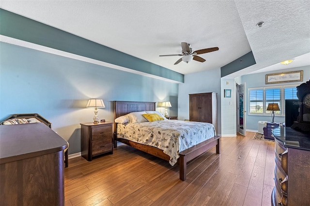 bedroom with a textured ceiling, ceiling fan, hardwood / wood-style flooring, and baseboards