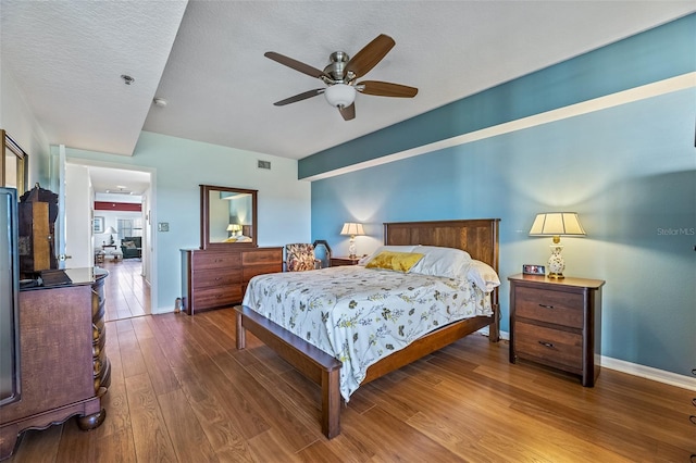 bedroom with baseboards, visible vents, a ceiling fan, wood finished floors, and a textured ceiling