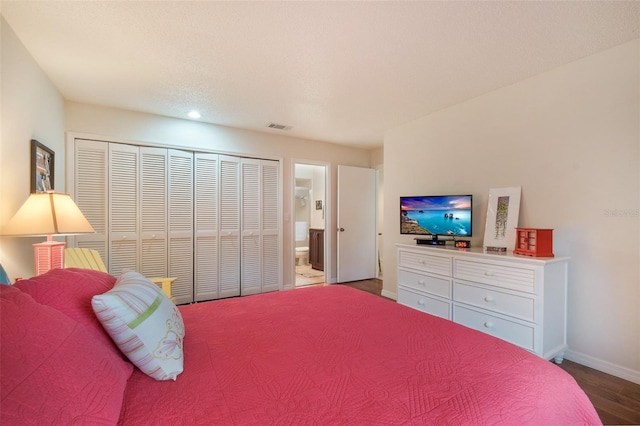 bedroom with wood finished floors, visible vents, baseboards, a closet, and ensuite bath