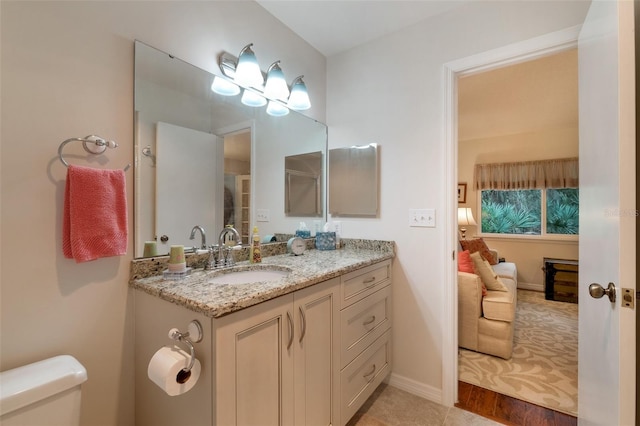 bathroom featuring toilet, baseboards, and vanity