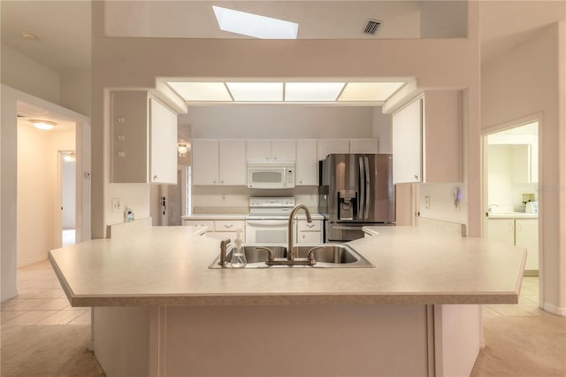 kitchen with white appliances, light countertops, a peninsula, and white cabinetry