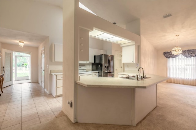 kitchen with a peninsula, a sink, white cabinets, light countertops, and stainless steel fridge