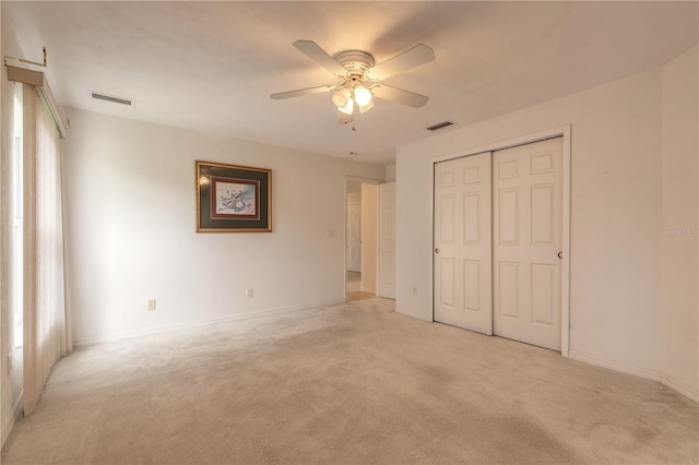 unfurnished bedroom with a ceiling fan, a closet, light colored carpet, and visible vents