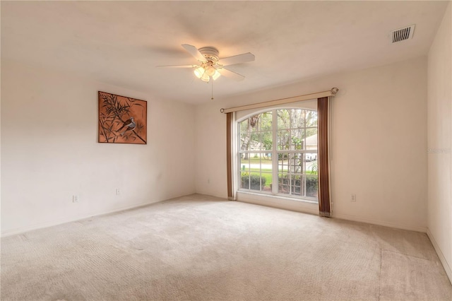 empty room featuring baseboards, visible vents, a ceiling fan, and light colored carpet