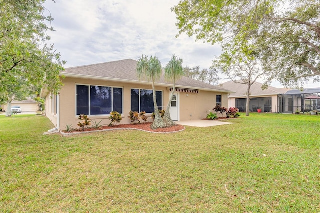 rear view of property with a yard and stucco siding