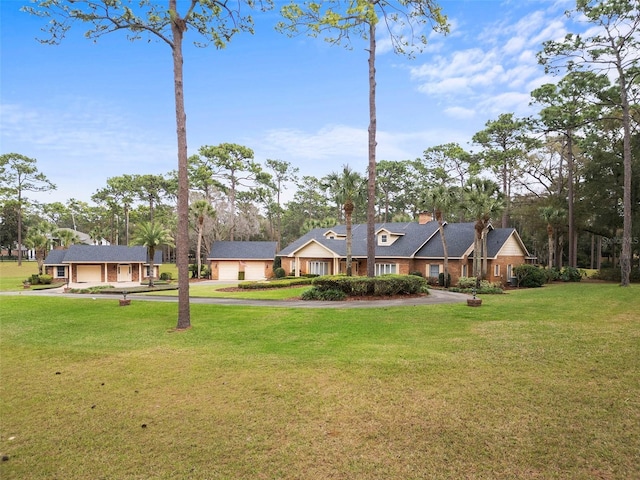 view of front of house featuring a garage, a chimney, and a front lawn