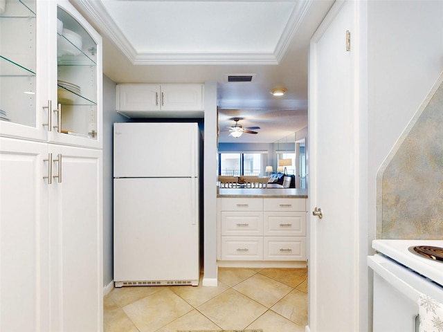 kitchen with light tile patterned floors, visible vents, white cabinets, freestanding refrigerator, and crown molding