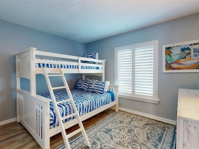 bedroom featuring a textured ceiling, wood finished floors, and baseboards