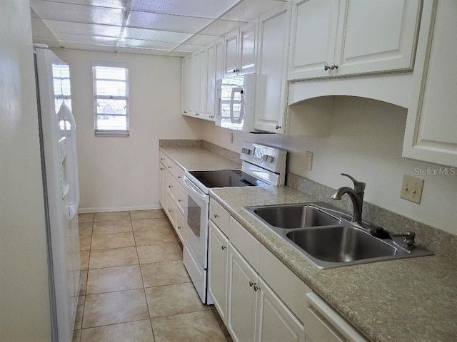 kitchen featuring white appliances, white cabinets, a sink, and light tile patterned floors