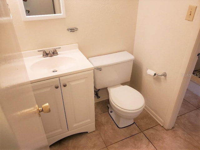 half bathroom featuring baseboards, vanity, toilet, and tile patterned floors