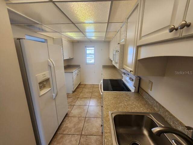 101 N Riverside Dr Unit 2090, New Smyrna Beach, FL 32168 - kitchen featuring white appliances, a sink, light tile patterned flooring, a drop ceiling, and baseboards