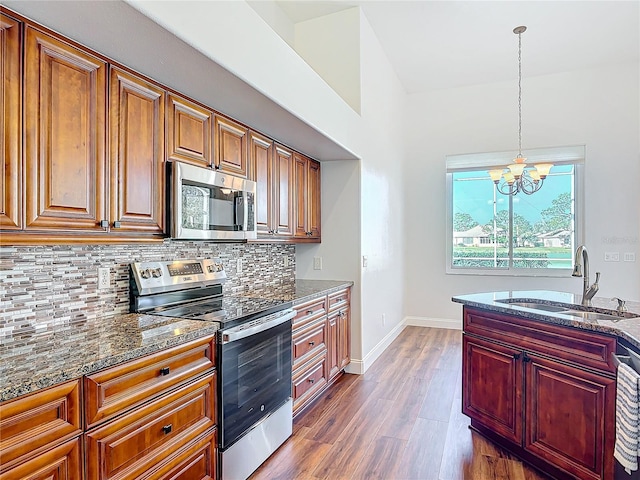 6456 Cypress Springs Pkwy, Port Orange, FL 32128 - kitchen featuring a sink, stainless steel appliances, dark stone counters, an inviting chandelier, and decorative backsplash