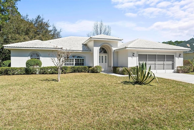 mediterranean / spanish house with an attached garage, stucco siding, concrete driveway, and a front yard