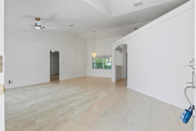 unfurnished living room featuring arched walkways, ceiling fan, light tile patterned floors, light colored carpet, and visible vents