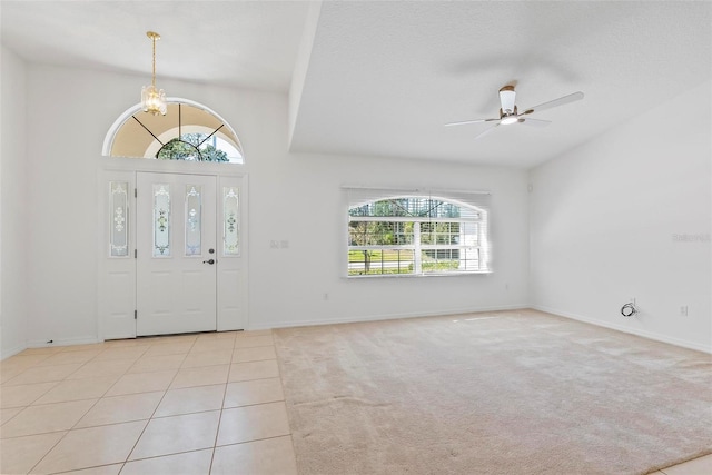 entrance foyer with a textured ceiling, light tile patterned flooring, light carpet, ceiling fan with notable chandelier, and baseboards