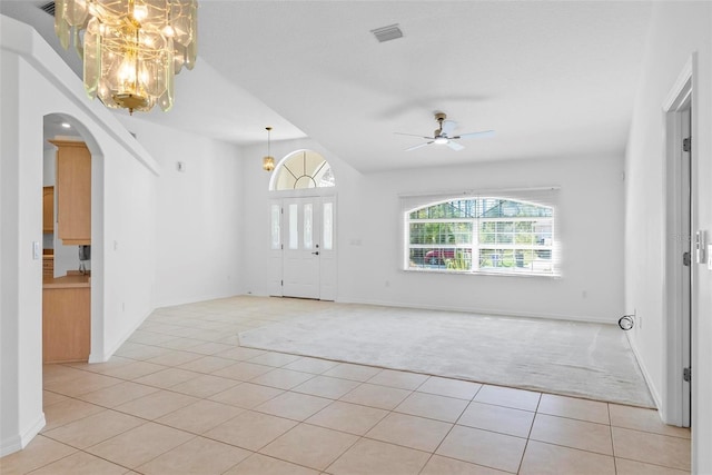 interior space with arched walkways, visible vents, light carpet, light tile patterned flooring, and ceiling fan with notable chandelier