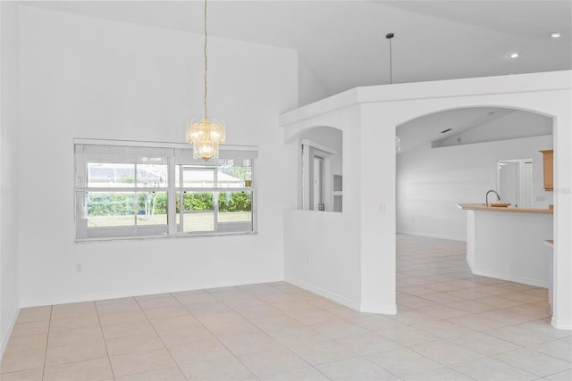 empty room with arched walkways, high vaulted ceiling, light tile patterned flooring, and an inviting chandelier