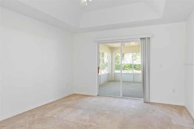 unfurnished room featuring light carpet, baseboards, and a tray ceiling