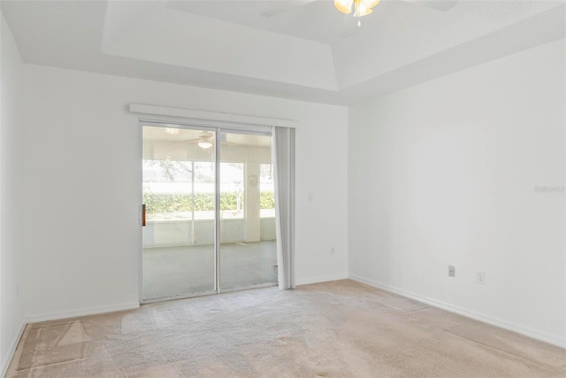 spare room with light carpet, a raised ceiling, and a ceiling fan