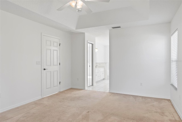 unfurnished room featuring baseboards, a raised ceiling, visible vents, and light colored carpet