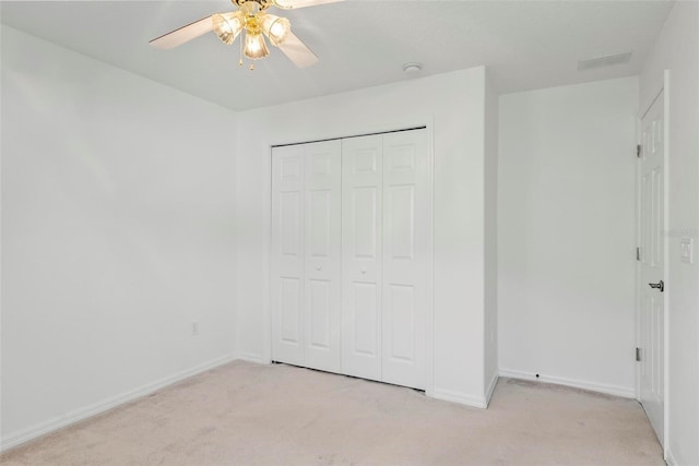 unfurnished bedroom featuring light carpet, a closet, a ceiling fan, and baseboards