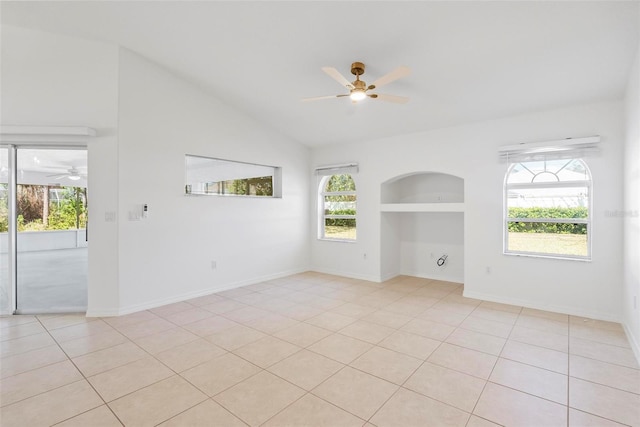 empty room with lofted ceiling, built in features, a ceiling fan, and light tile patterned flooring