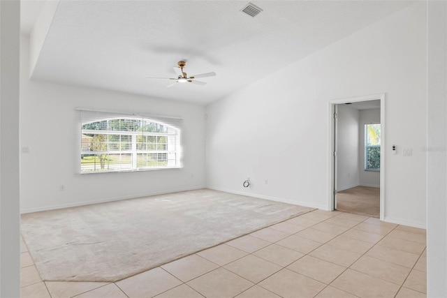 empty room featuring lofted ceiling, a wealth of natural light, visible vents, and light carpet