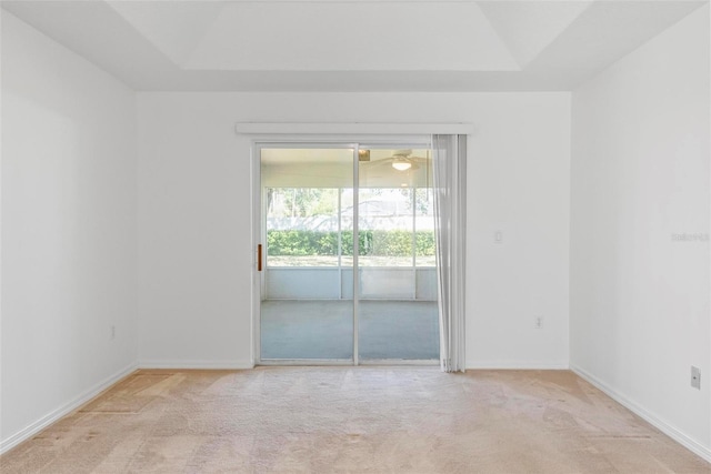 unfurnished room featuring baseboards, a tray ceiling, and light colored carpet