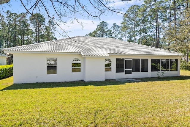 back of house featuring a tile roof, a yard, and stucco siding