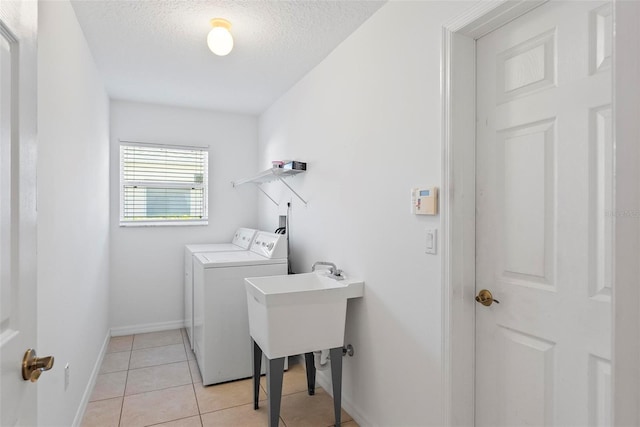 laundry area with laundry area, baseboards, a textured ceiling, separate washer and dryer, and light tile patterned flooring